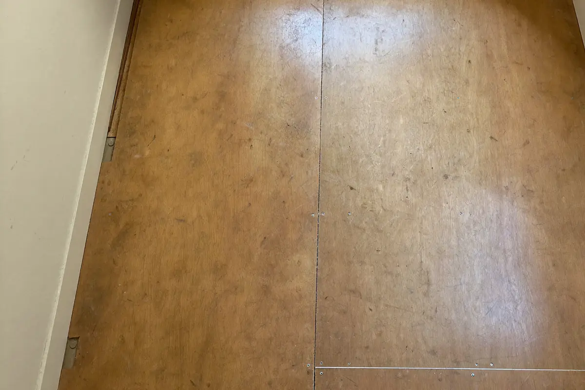 Kale houten plaatvloer in een lege huurkamer nadat het laminaat is verwijderd, geveegd en klaar voor de oplevering